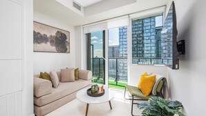Ein modernes Wohnzimmer mit einer Couch, einem Couchtisch und einem großen Fenster mit Blick auf die Stadt.
