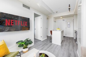 A modern interior with a large Netflix poster, a kitchen area, and a dining space. - Modern 22nd Floor 1BR | South-Facing City Views | Indoor Parking | North York (Toronto)