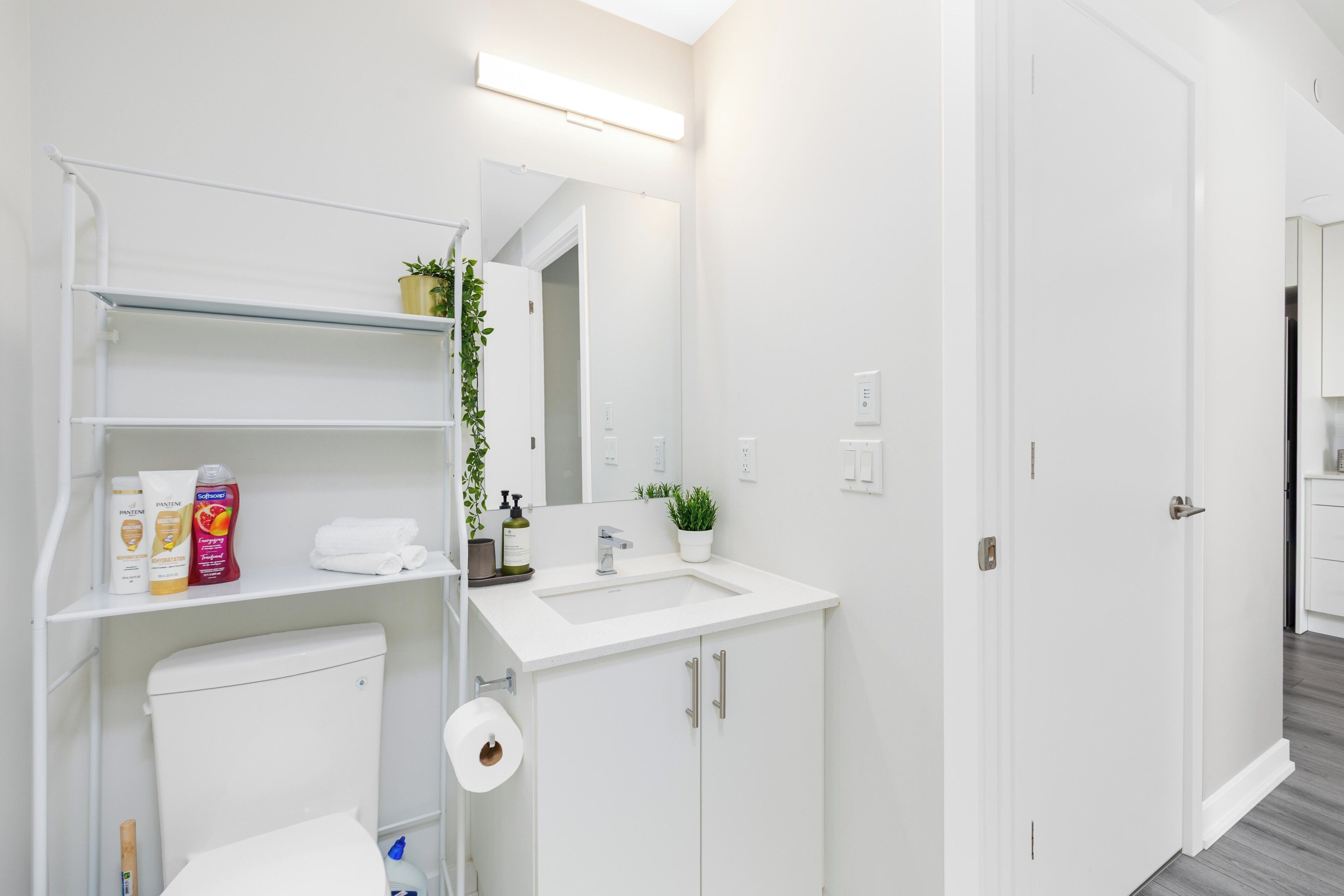 A modern bathroom with a toilet, sink, and shelves.