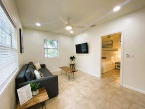 Una sala de estar moderna con un sofá, una mesa de centro, un televisor y un ventilador de techo.