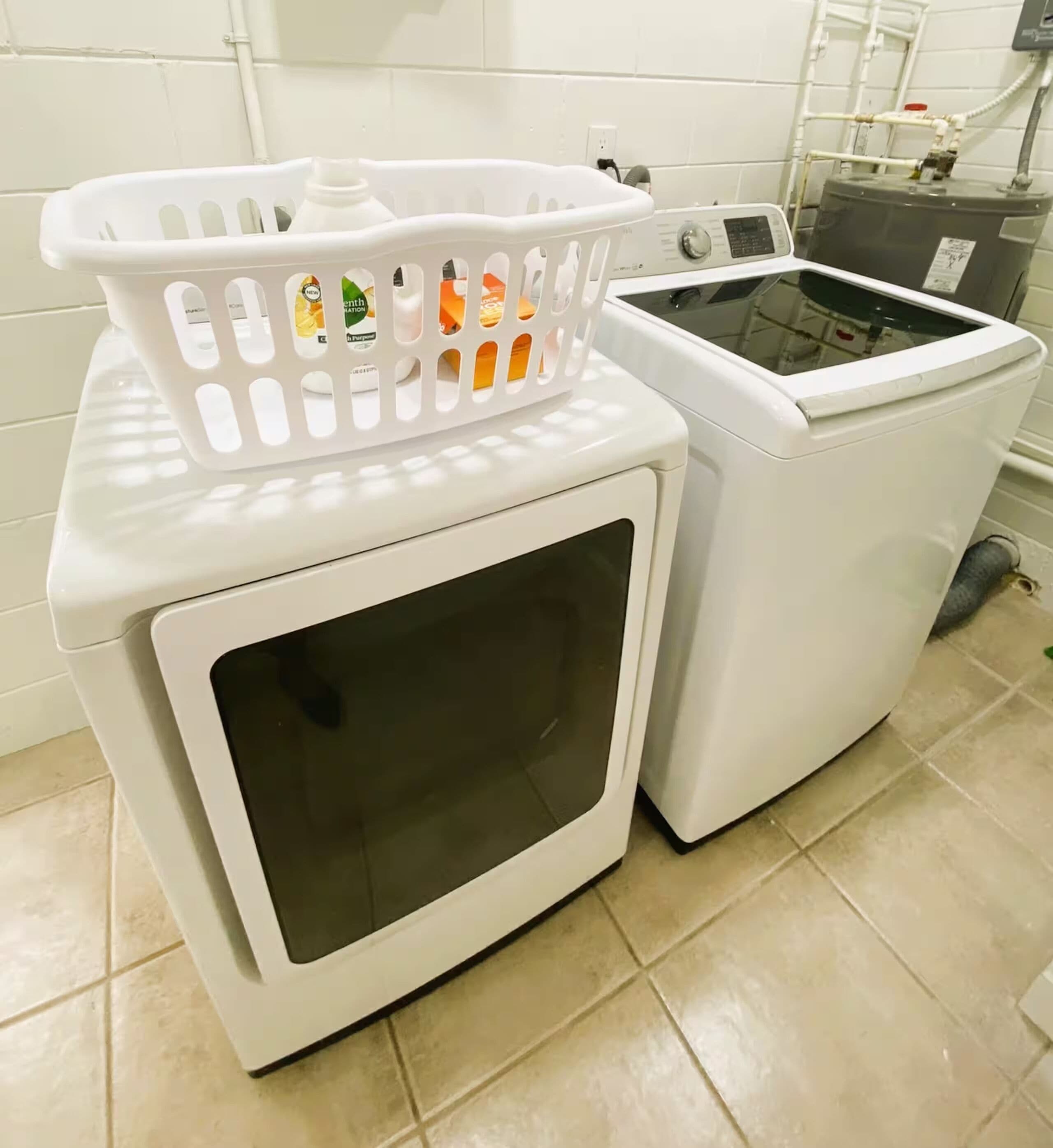 Een wasruimte met twee gestapelde wasmachines en een witte plastic wasmand erboven.