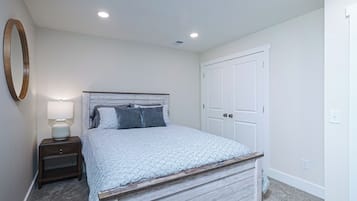 Quarto com cama, mesa de cabeceira, abajur e guarda-roupa.
