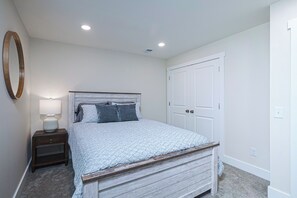 A bedroom with a bed, nightstand, lamp, and a wardrobe.