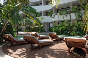 A poolside area with wooden loungers, a hot tub, and lush tropical plants. - Elements 326/Studio with Jacuzzi 233/Includes access to the beach club (Tulum)