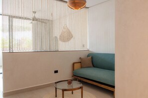 A room with a green sofa, a glass coffee table, and a window with vertical blinds. - Elements 326/Studio with Jacuzzi 233/Includes access to the beach club (Tulum)