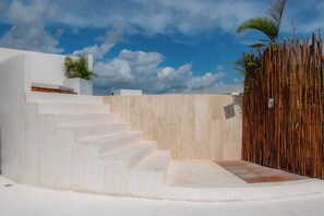 A modern outdoor staircase leading to a white building with a wooden fence and plants. - Elements 326/Studio with Jacuzzi 233/Includes access to the beach club (Tulum)