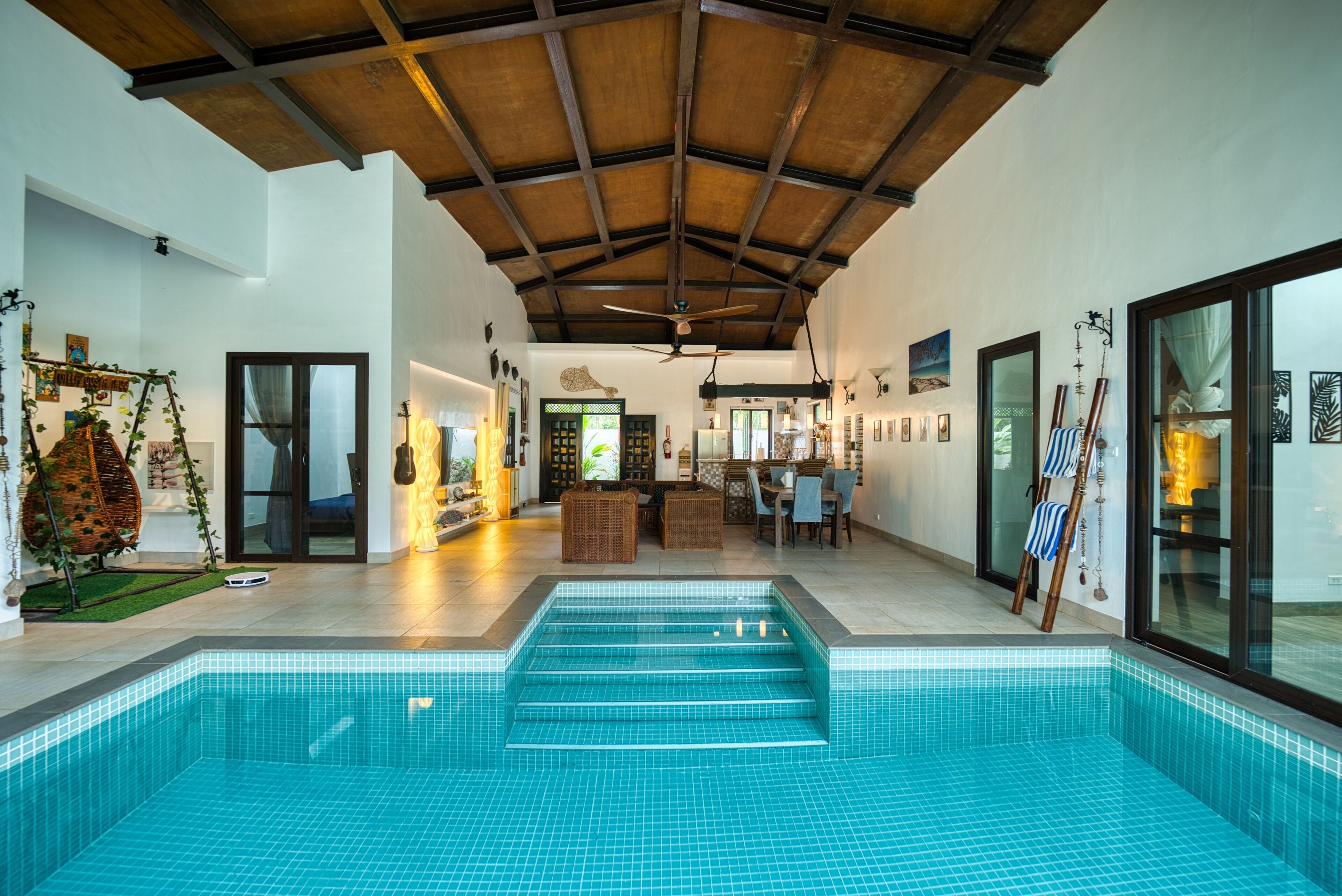 A spacious indoor swimming pool with a tiled floor and a wooden ceiling.