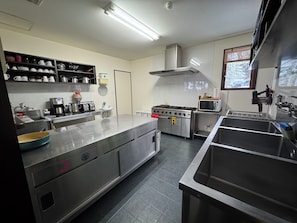 A modern kitchen with stainless steel appliances, a large island, and ample counter space. - Bears Den Hakuba | Private Lodge | 5 Bedrooms with Private Bathrooms, Hot Tub, and Walking Distance to the Ski Resort (白馬村)