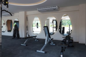 A gym with various exercise equipment, large mirrors, and a view of the outdoors through arched windows. - Elements 326/Studio with Jacuzzi 234/ Beach club access included (Tulum)