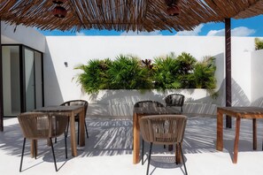 An outdoor patio with wicker furniture, a thatched roof, and a wall-mounted plant display. - Vrbo Property (Tulum)