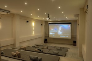 A modern cinema room with rows of reclining seats, a large screen, and a projector. - Elements 326/Studio with Jacuzzi 234/ Beach club access included (Tulum)