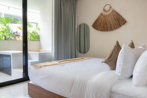 A modern bedroom with a large bed, a view of greenery through a sliding door, and a wall-mounted decorative item. - Vrbo Property (Tulum)