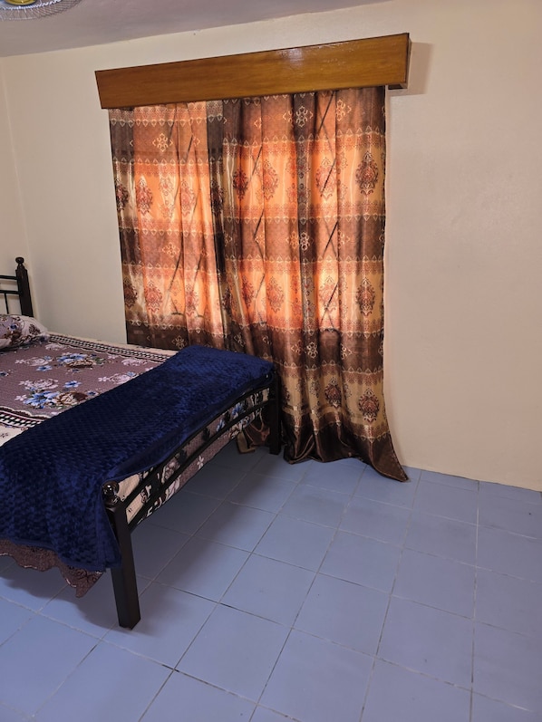 A bedroom with a bed, a headboard, and a curtain.