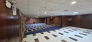 A conference room with a blue carpet, white and brown patterned floor, wooden walls, and ceiling-mounted lights. - Mabani Rawaf Hotel (Makkah)