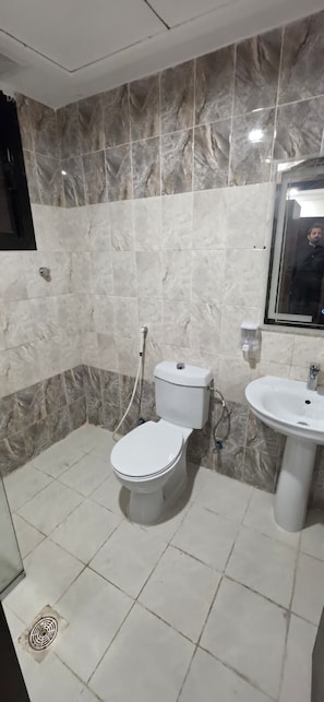 A bathroom with a toilet, sink, and marble walls.