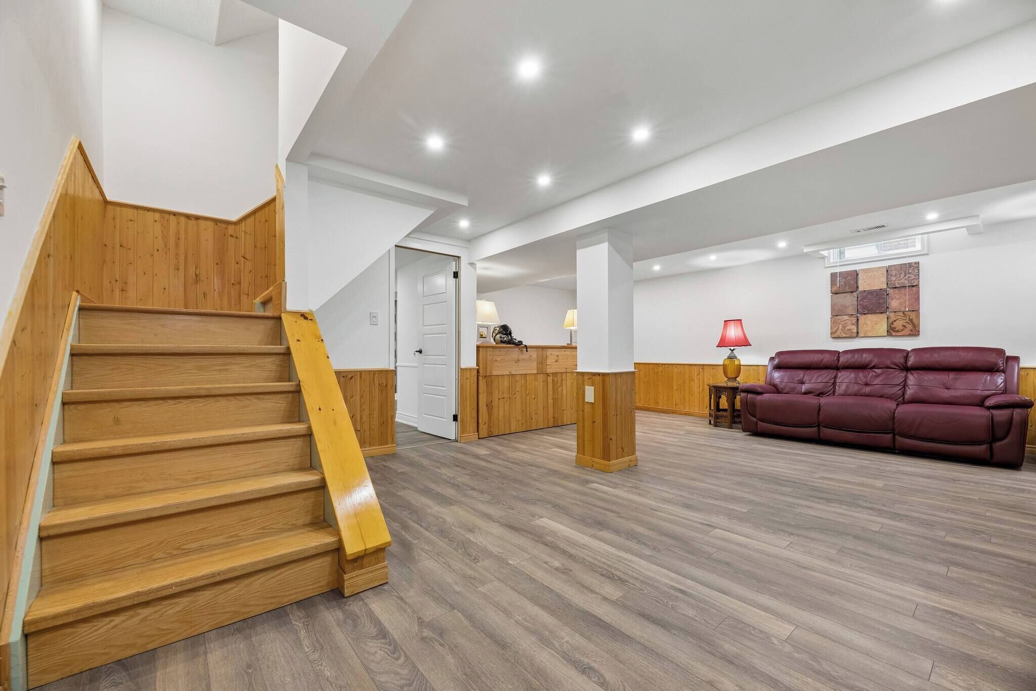 A modern interior with a wooden staircase, a reception desk, a leather sofa, and a wooden floor.