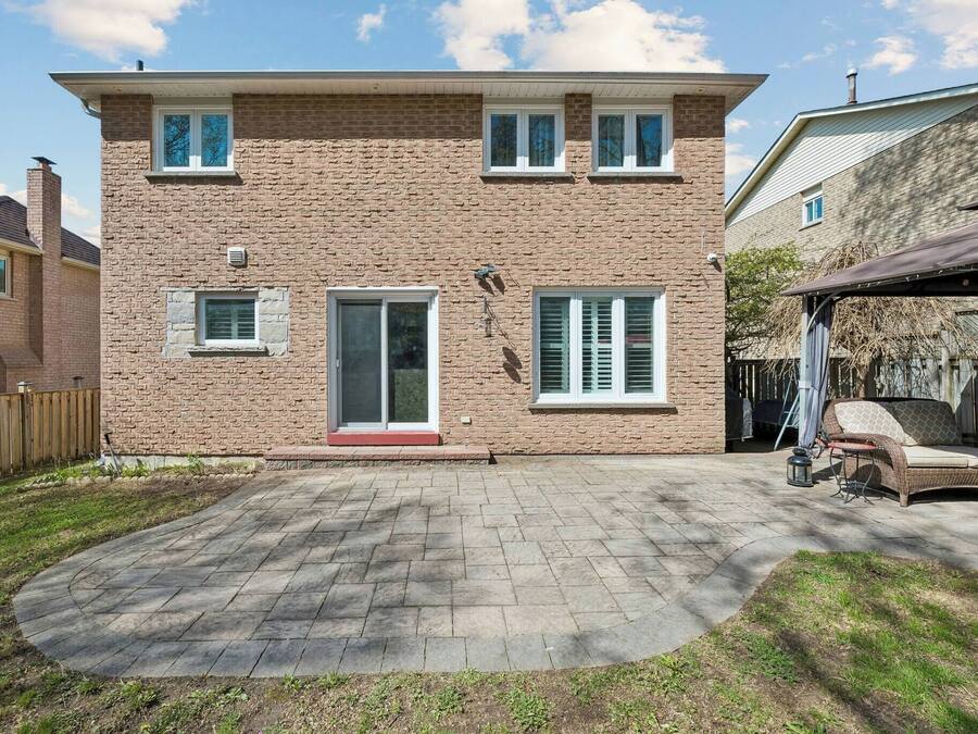 A two-story brick house with a covered patio, a front door, and a small side window.