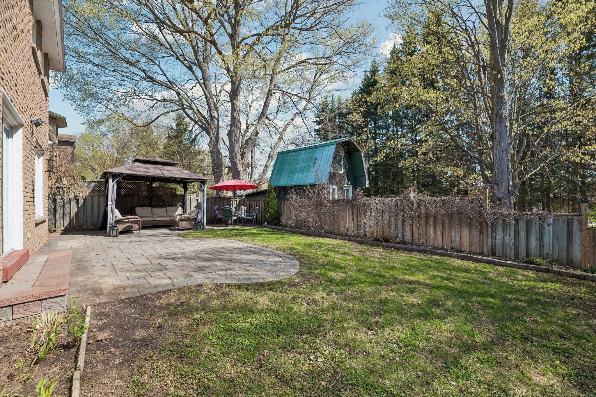 A backyard with a patio, a covered seating area, and a wooden fence.
