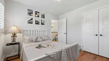 A bedroom with a bed, a nightstand, a lamp, a door, and a staircase.