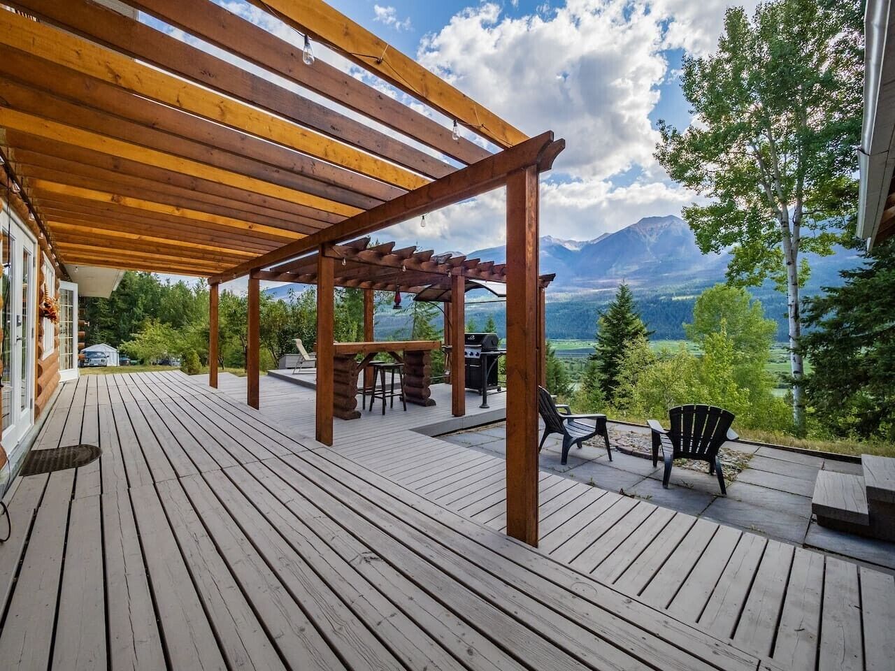 A wooden deck with a pergola, outdoor seating, and a scenic mountain view.