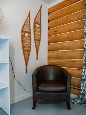 Ein Zimmer mit einer Wand aus Holzleisten, einem braunen Ledersessel und zwei an der Wand befestigten Korbschmuck.