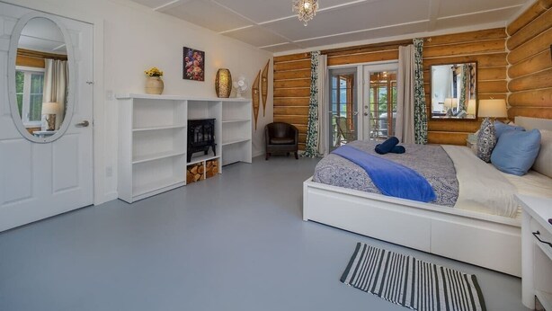 Quarto com cama grande, guarda-roupa branco, mesa pequena, cadeira e lareira.