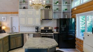 Cozinha com ilha central, eletrodomésticos embutidos e um lustre.