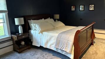 A bedroom with a bed, nightstands, a window, and wall art.