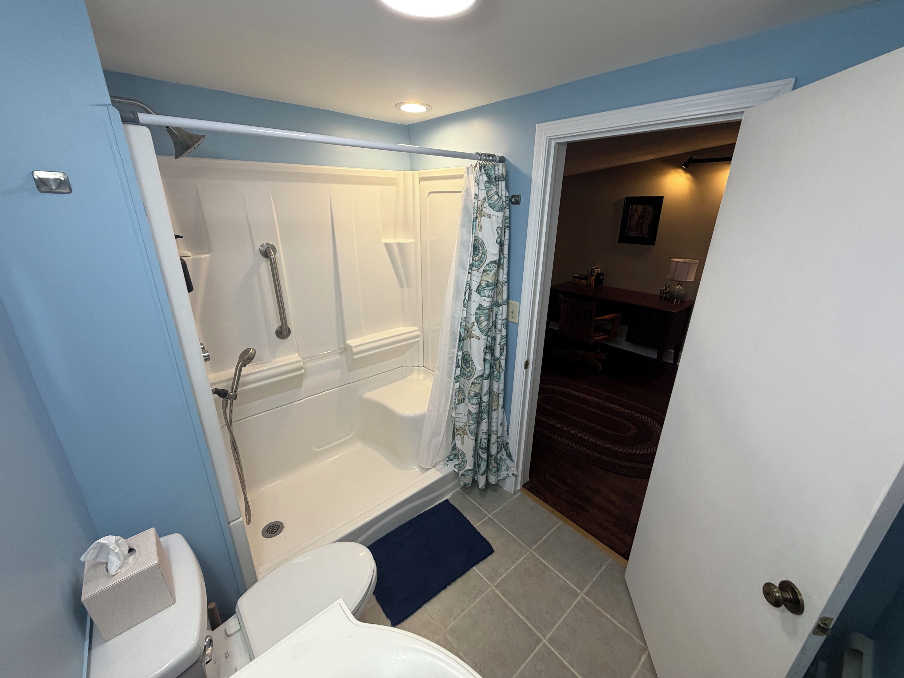 Une salle de bain avec douche, toilettes et une porte donnant sur un coin repas.