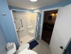 A bathroom with a shower, toilet, and a door leading to a dining area. - West & Vine - Lake Erie Fishing & Wine Country (Ripley)