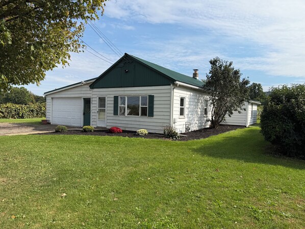 A single-story house with a green roof, a garage, and a well-maintained lawn. - West & Vine - Lake Erie Fishing & Wine Country (Ripley)