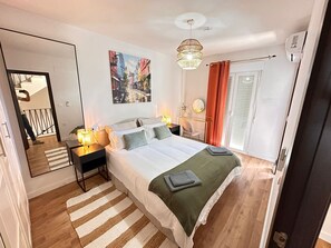 A bedroom with a bed, bedside lamps, a painting, a mirror, and a window with curtains. - Vistas Rio Verde, Stunning unobstructed views of the valley with 3 terraces! (Almuñécar)