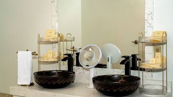 A bathroom with two black bowls with gold patterns, a white towel, and a mirror with a ring light.