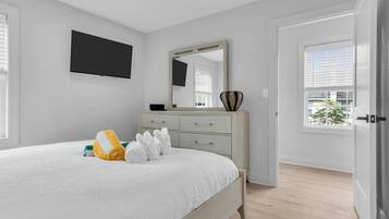 Ein Schlafzimmer mit einem Bett, einem Schminktisch, einem Spiegel und einem an der Wand befestigten Fernseher.