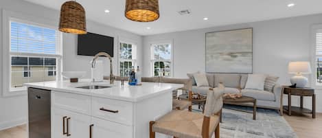 A modern kitchen with a central island, white cabinetry, and a built-in dishwasher.