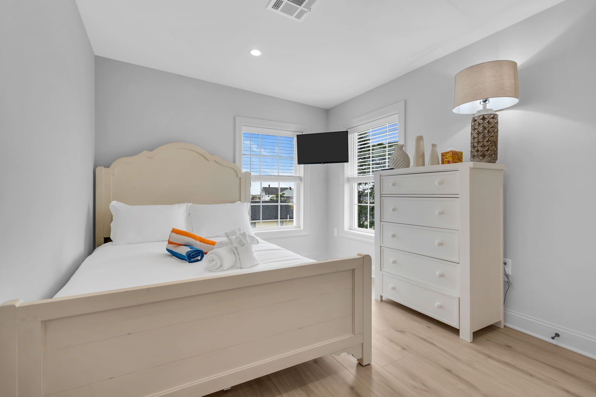 A bedroom with a bed, a dresser, a TV, and a window.