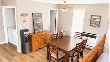 A dining area with a wooden table and chairs, a refrigerator, a wooden cabinet, and a ceiling fan.