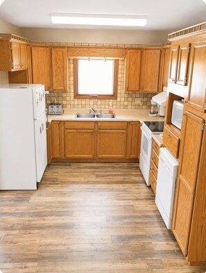 A kitchen with wooden cabinets, a white refrigerator, a toaster, a sink, and a microwave.