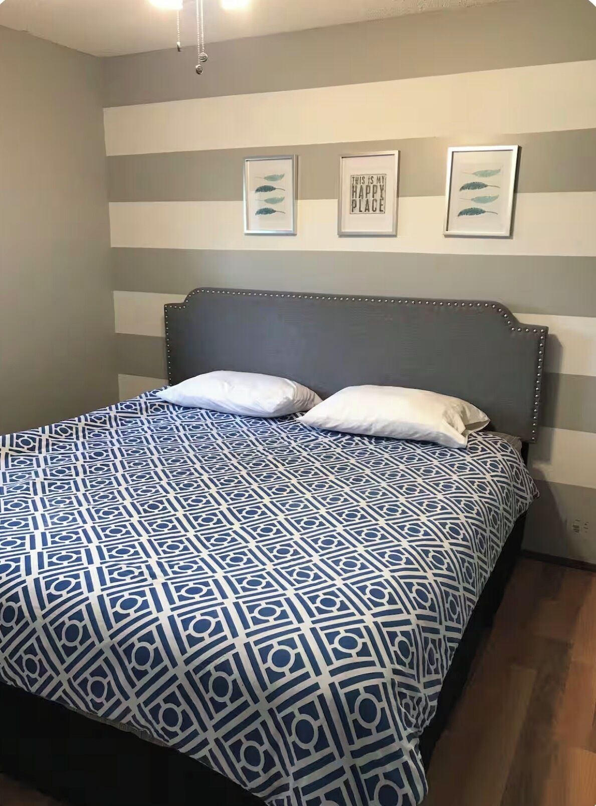 A bed with a patterned bedspread, a headboard, and two pillows.