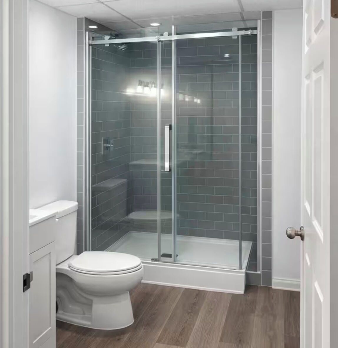 A modern bathroom with a glass-enclosed shower, a white toilet, and a wooden floor.