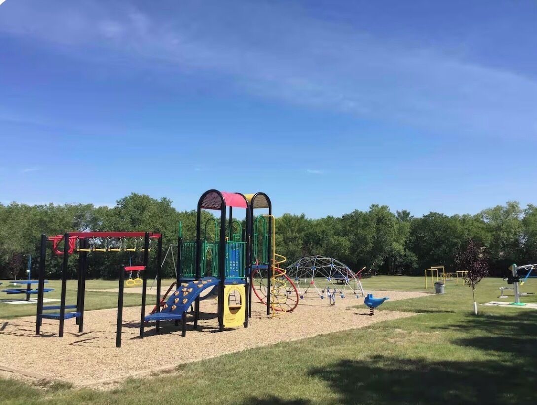 A playground with various play structures including a slide, swings, and climbing frames.
