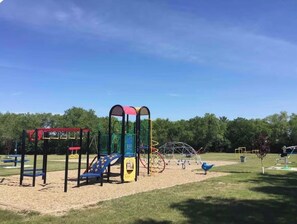 A playground with various play structures including a slide, swings, and climbing frames.