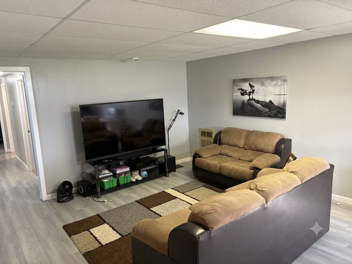 A living room with a sectional sofa, a flat-screen TV, and a framed picture on the wall.