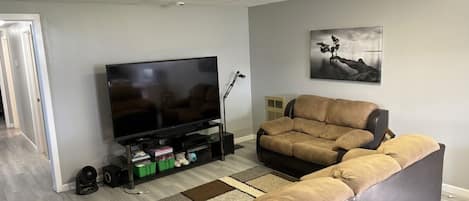 A living room with a sectional sofa, a flat-screen TV, and a framed picture on the wall.