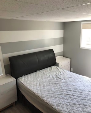 A bedroom with a bed, nightstands, and a window.