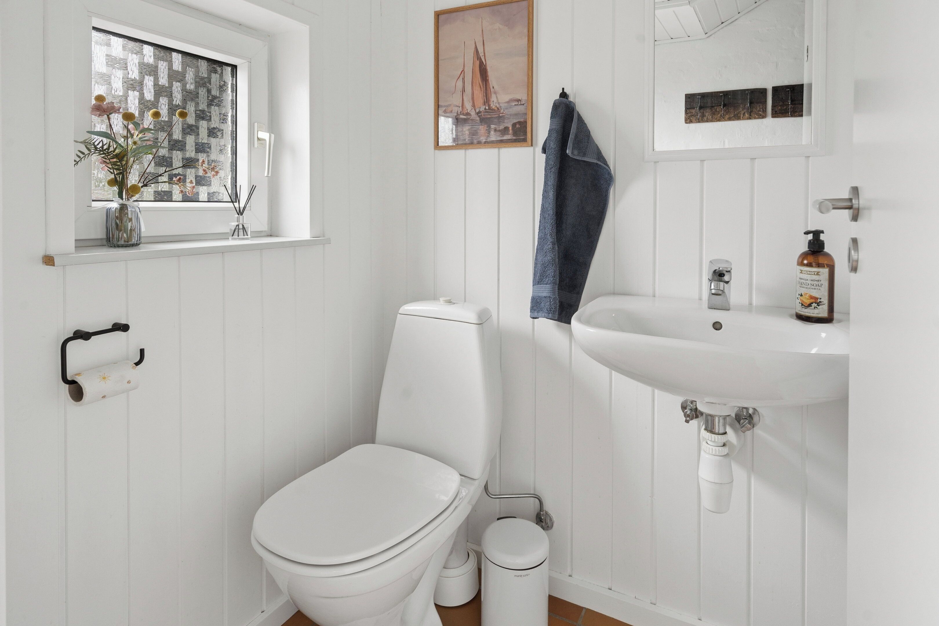 Un baño blanco con inodoro, lavamanos y ventana.