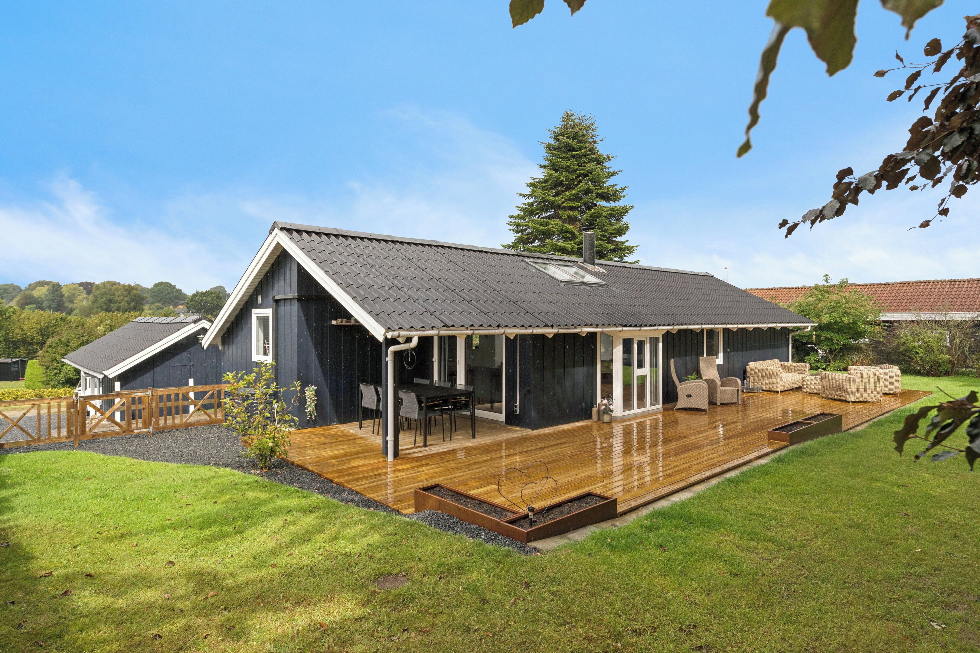 Een modern huis met een groot terras, een eethoek en een overdekte zithoek.