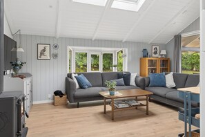 A living room with a grey sofa, a wooden coffee table, and a cabinet with glass doors. - Lovely, well-designed holiday home for 6 (Hejls)