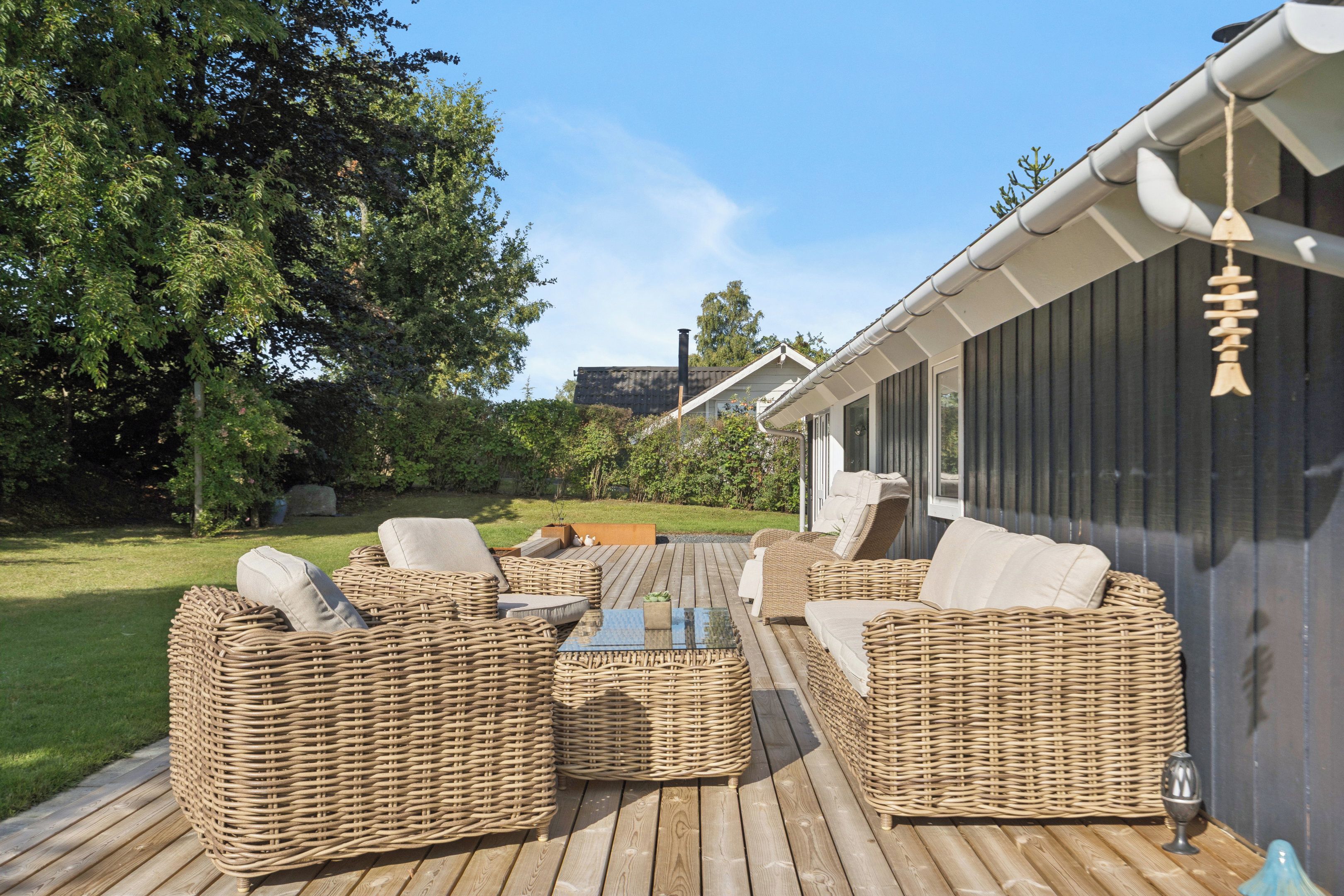 Un espace extérieur aménagé avec des meubles en osier et une terrasse en bois.