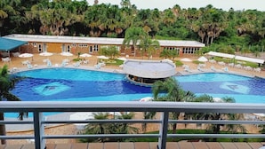 Et hotel med en stor swimmingpool, liggestole og et overdækket område.
